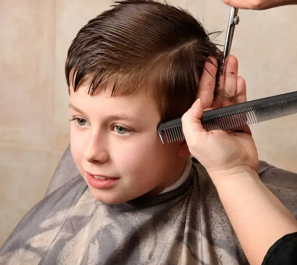 A young boy is getting his hair cut by a barber.