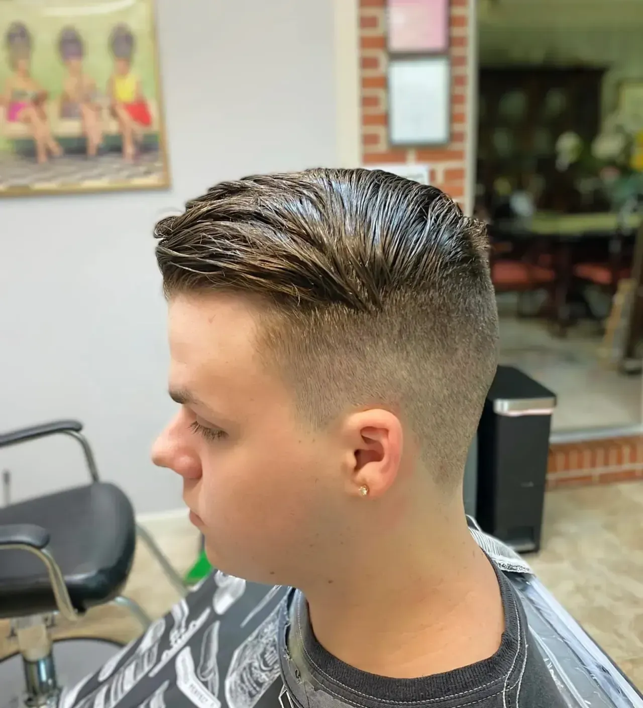 A young man is getting his hair cut at a barber shop.