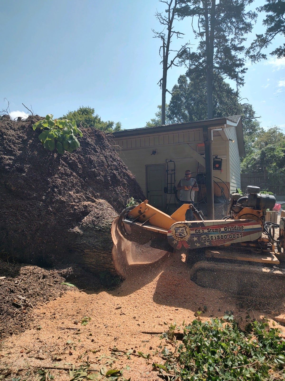 A large tree stump is being removed by a machine.