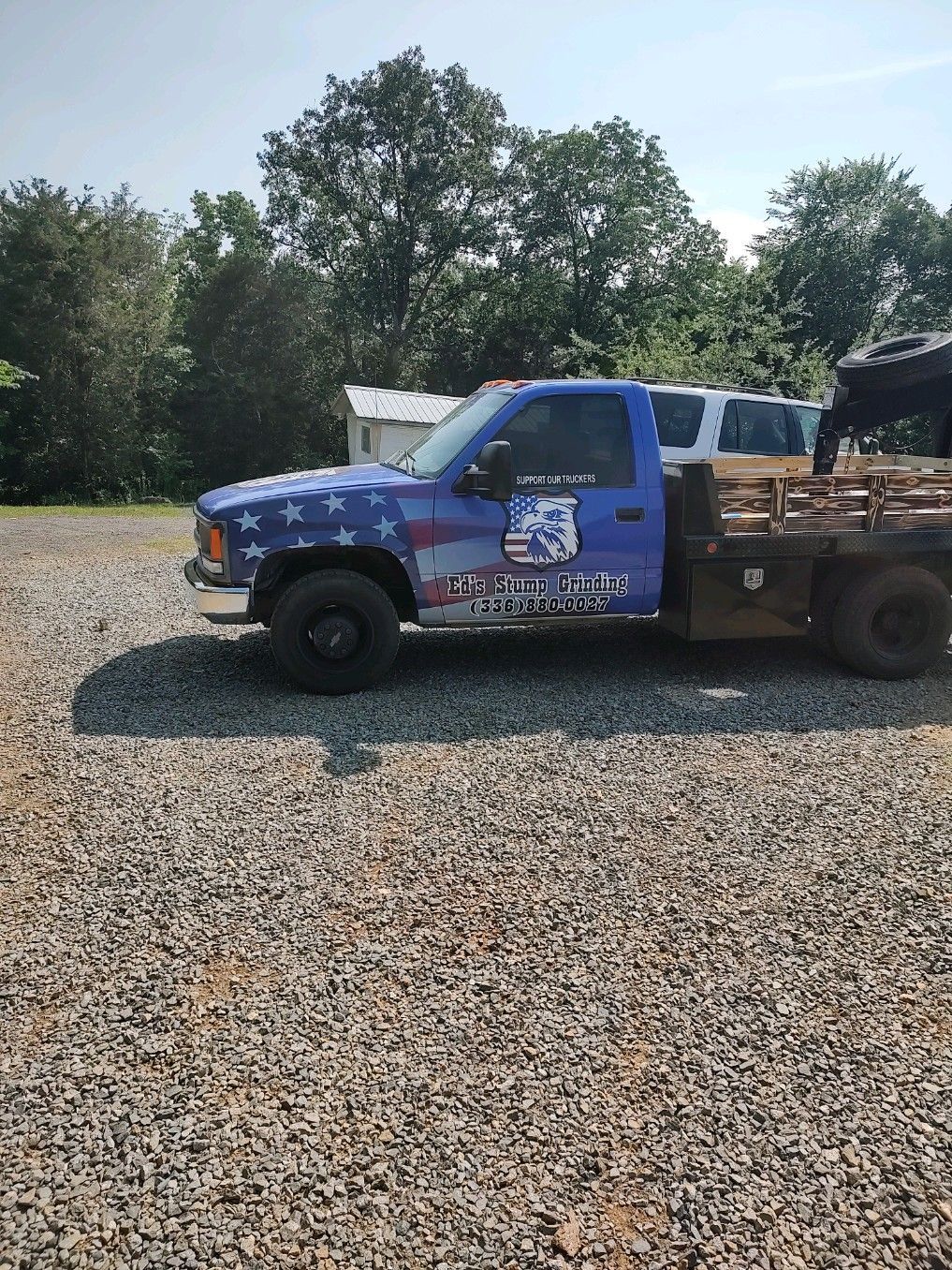 A blue tow truck is parked in a gravel lot.