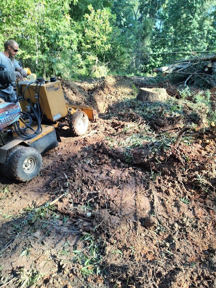 A man is riding a stump grinder in the dirt.