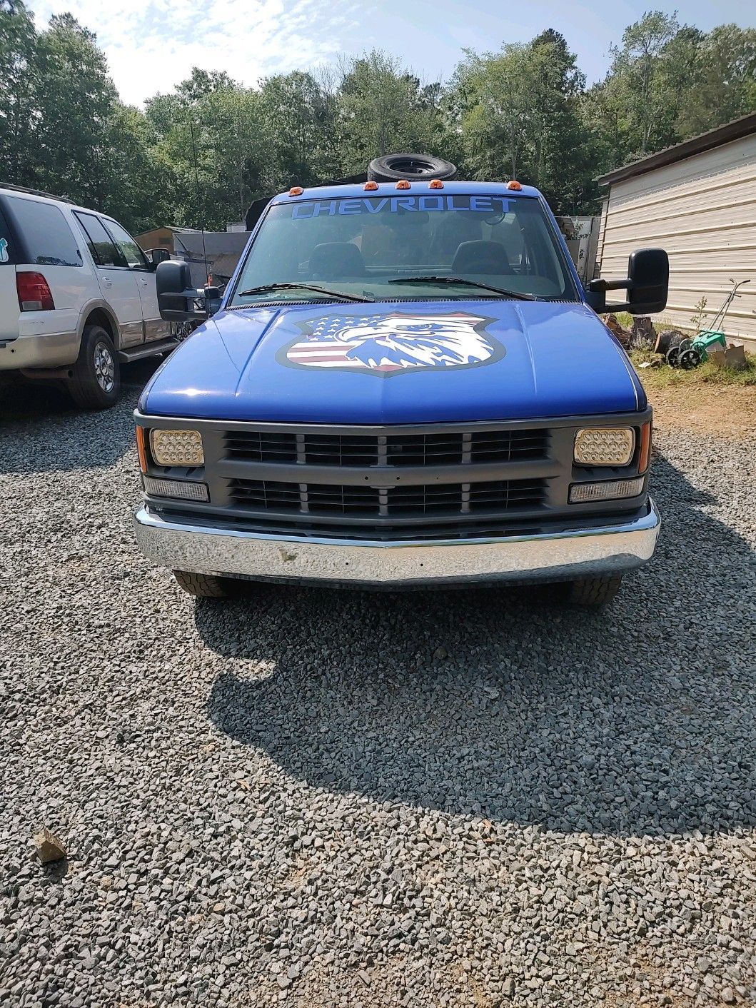 A blue truck is parked in a gravel lot.