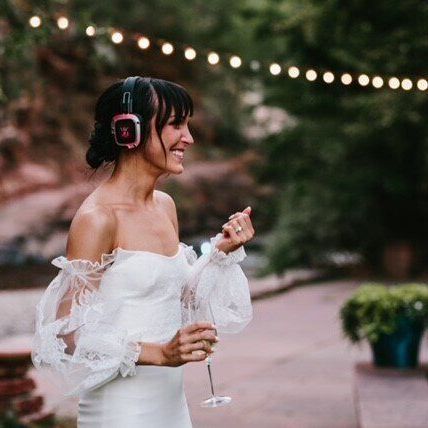 women in wedding dress holding a drink with silent disco headphones on