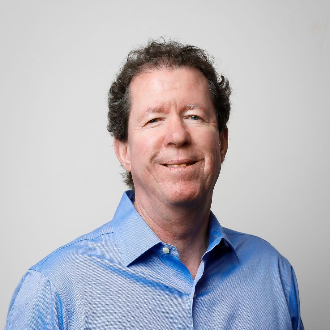 A man in a blue shirt is smiling for the camera.