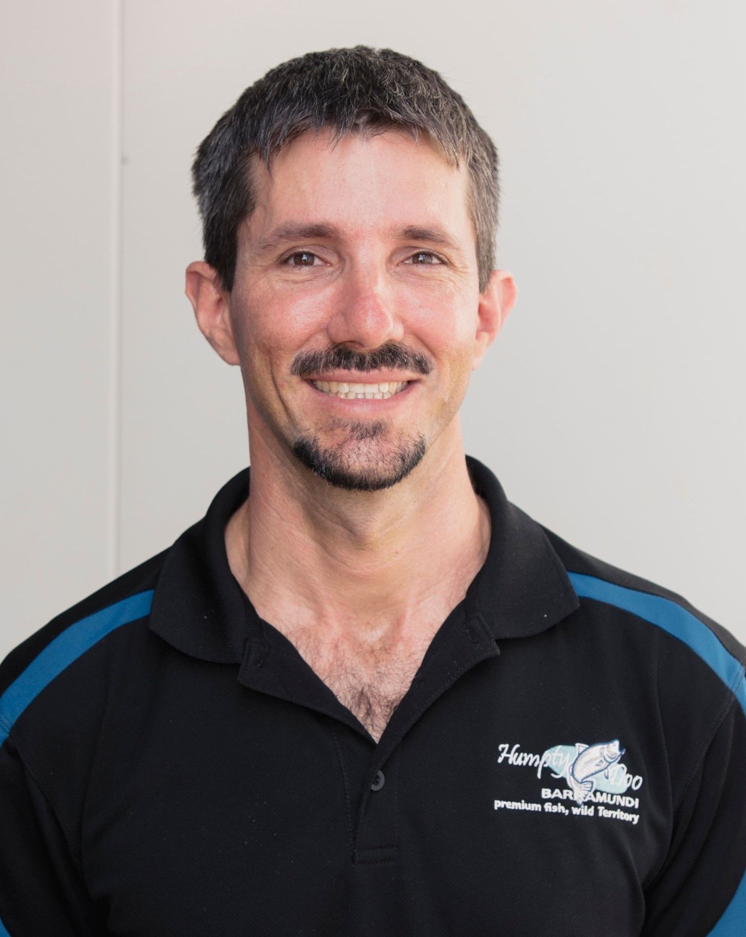 A man with a beard and mustache is wearing a black shirt with a horse on it