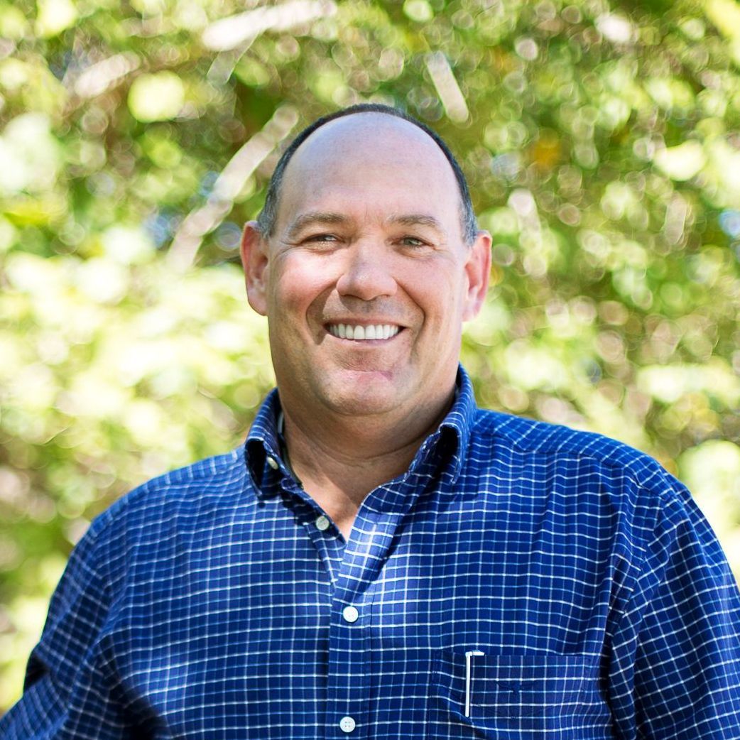 A man in a blue plaid shirt is smiling for the camera.