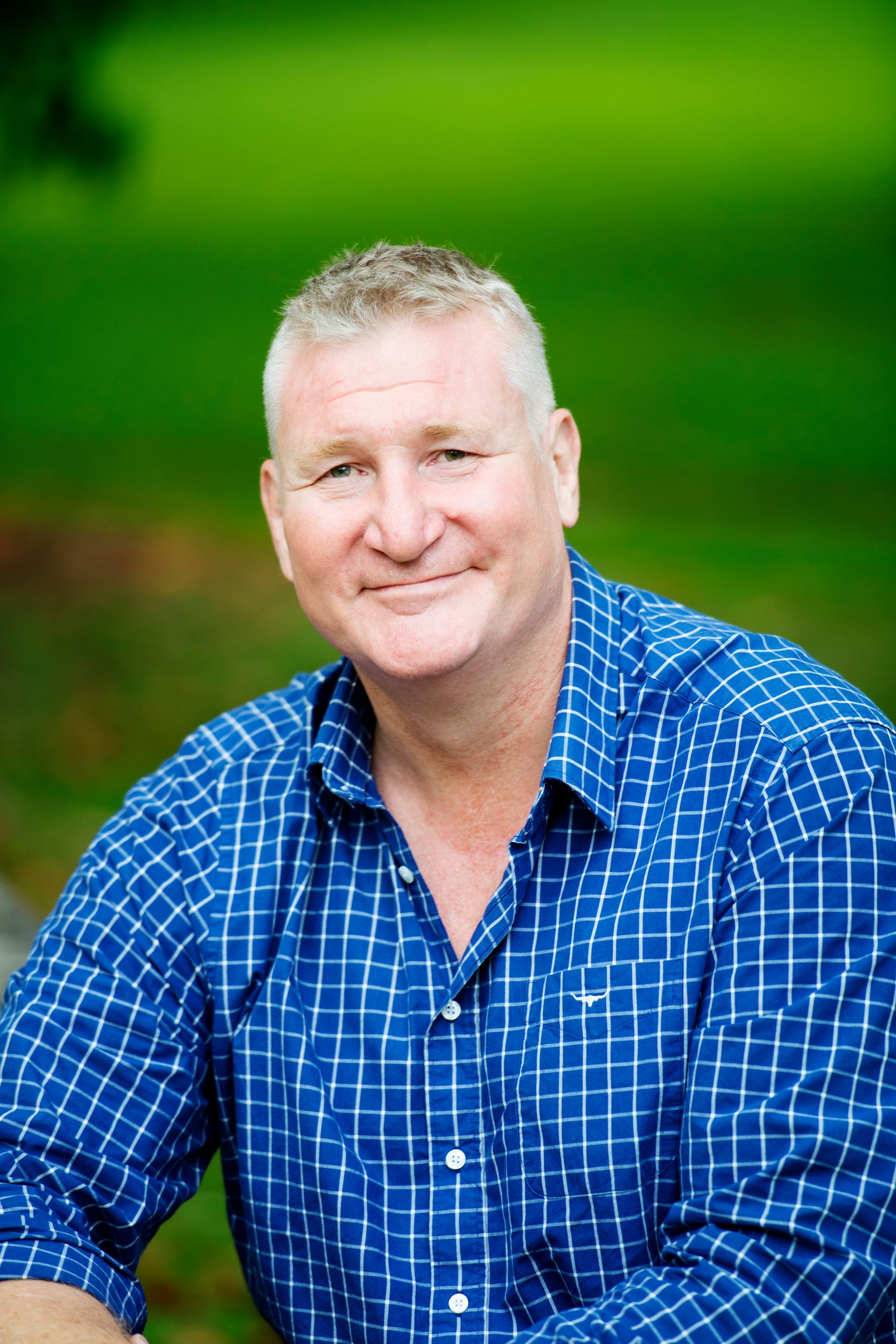 A man in a blue plaid shirt is smiling for the camera