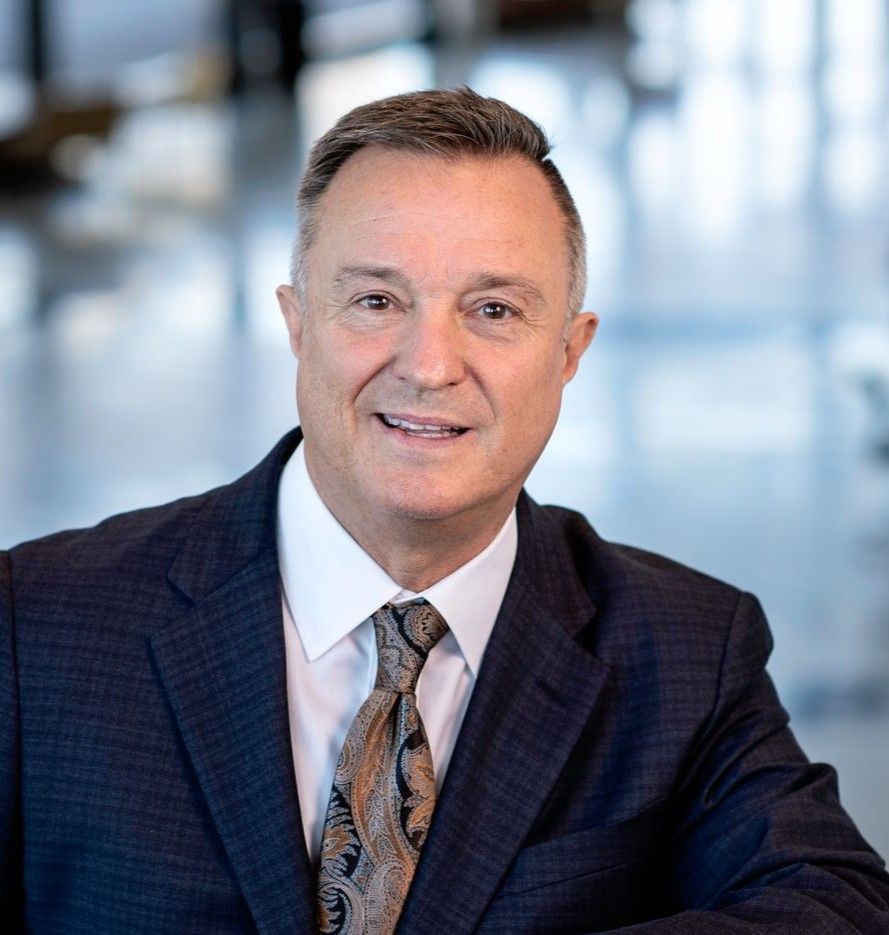 A man in a suit and tie is smiling for the camera.