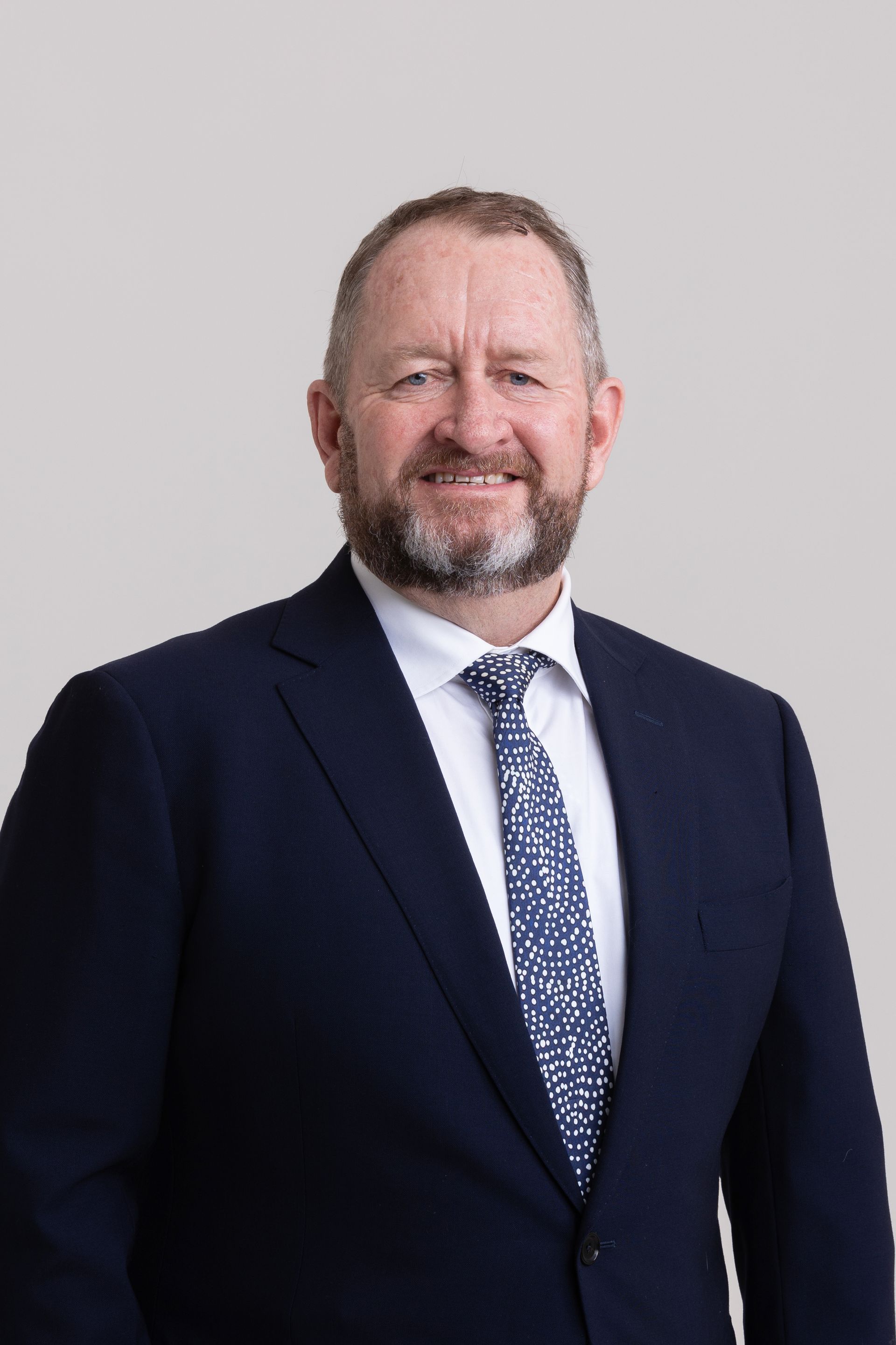 A man with a beard is wearing a suit and tie.