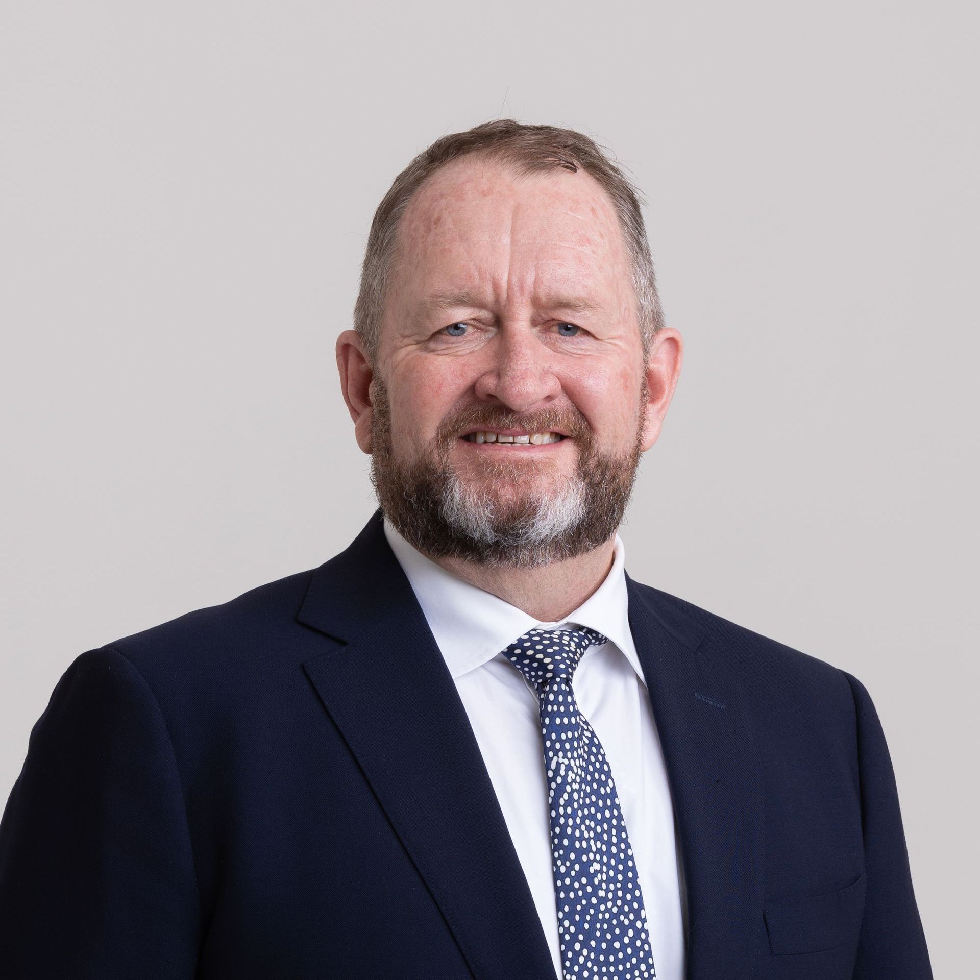 A man with a beard is wearing a suit and tie.