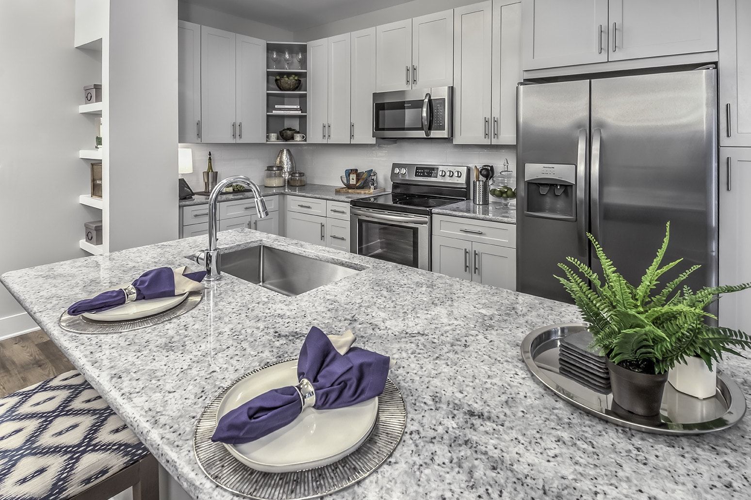 Kitchen with granite countertops, stainless steel appliances, and white cabinets.