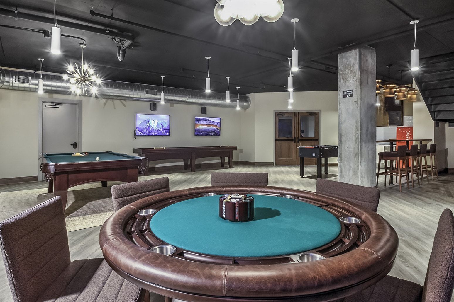 Game room with pool table, poker table, foosball, and bar area.