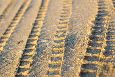 A close up of tire tracks in the sand on a beach.