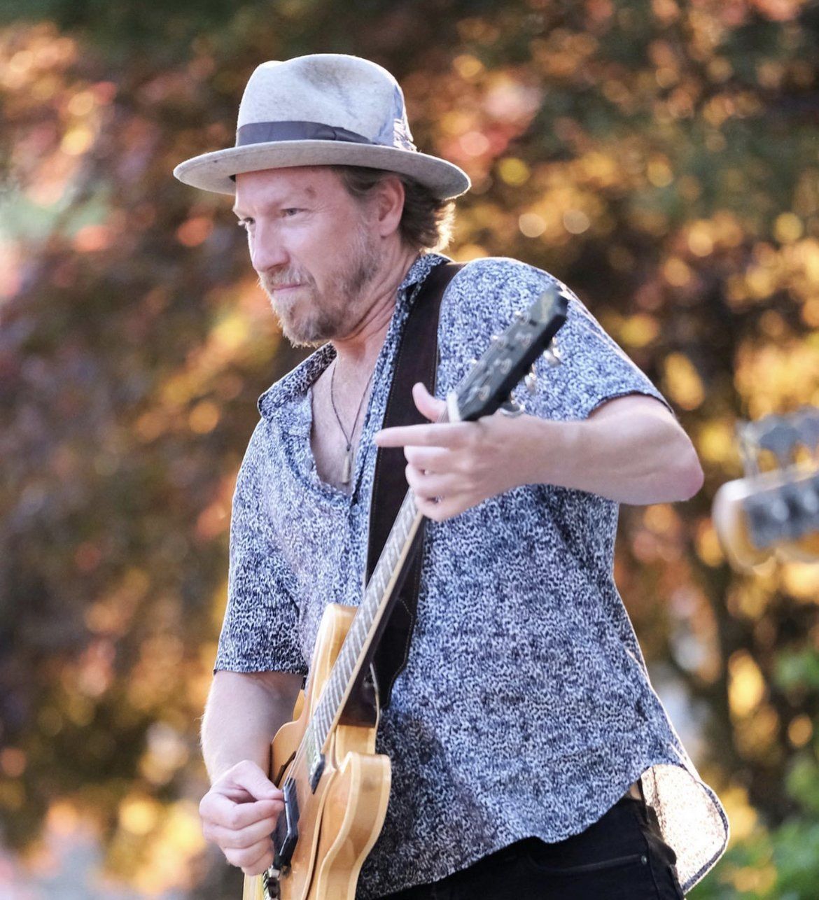 A man wearing a hat is playing a guitar