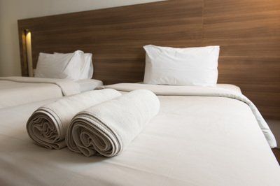 Two towels are rolled up on a bed in a hotel room.