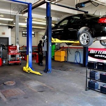 Auto repair shop with black car raised on a blue hydraulic lift and tools nearby