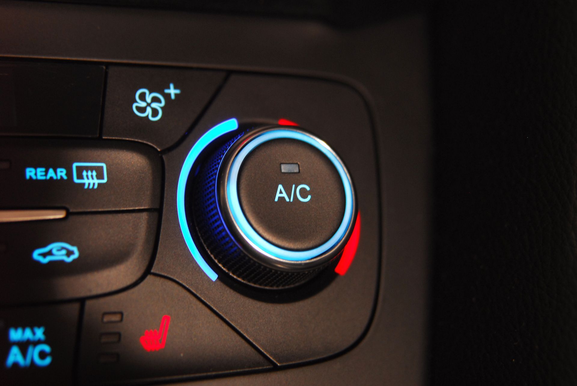 Car dashboard climate controls with A/C dial glowing blue and red, plus rear defrost and MAX A/C buttons
