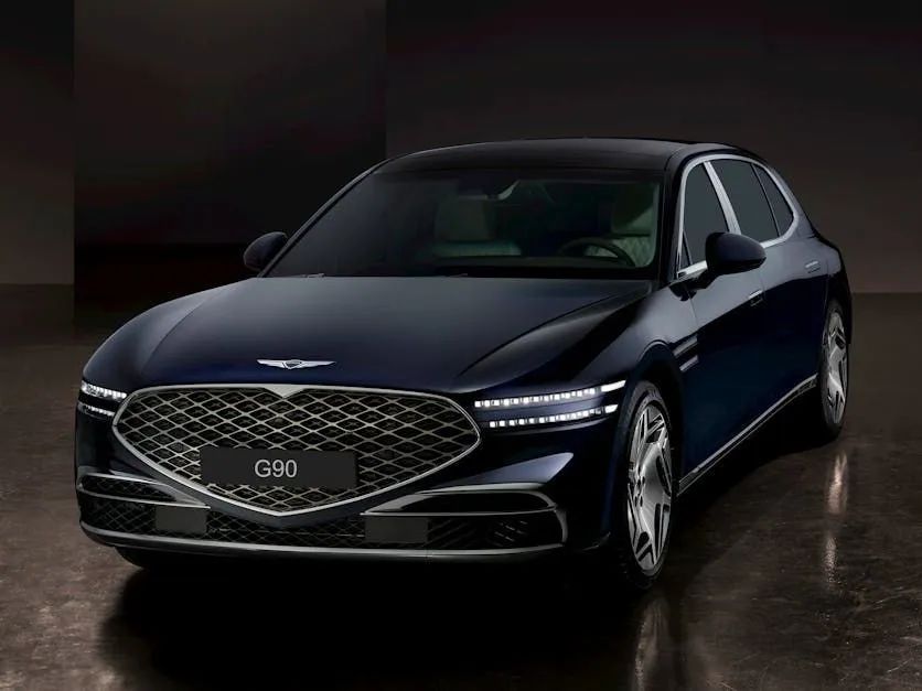 Dark blue luxury sedan with chrome grille, front view in a dim studio setting