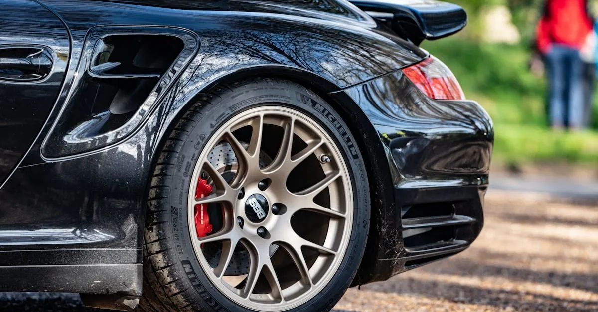 Black sports car rear wheel with red brake caliper on a dirt road
