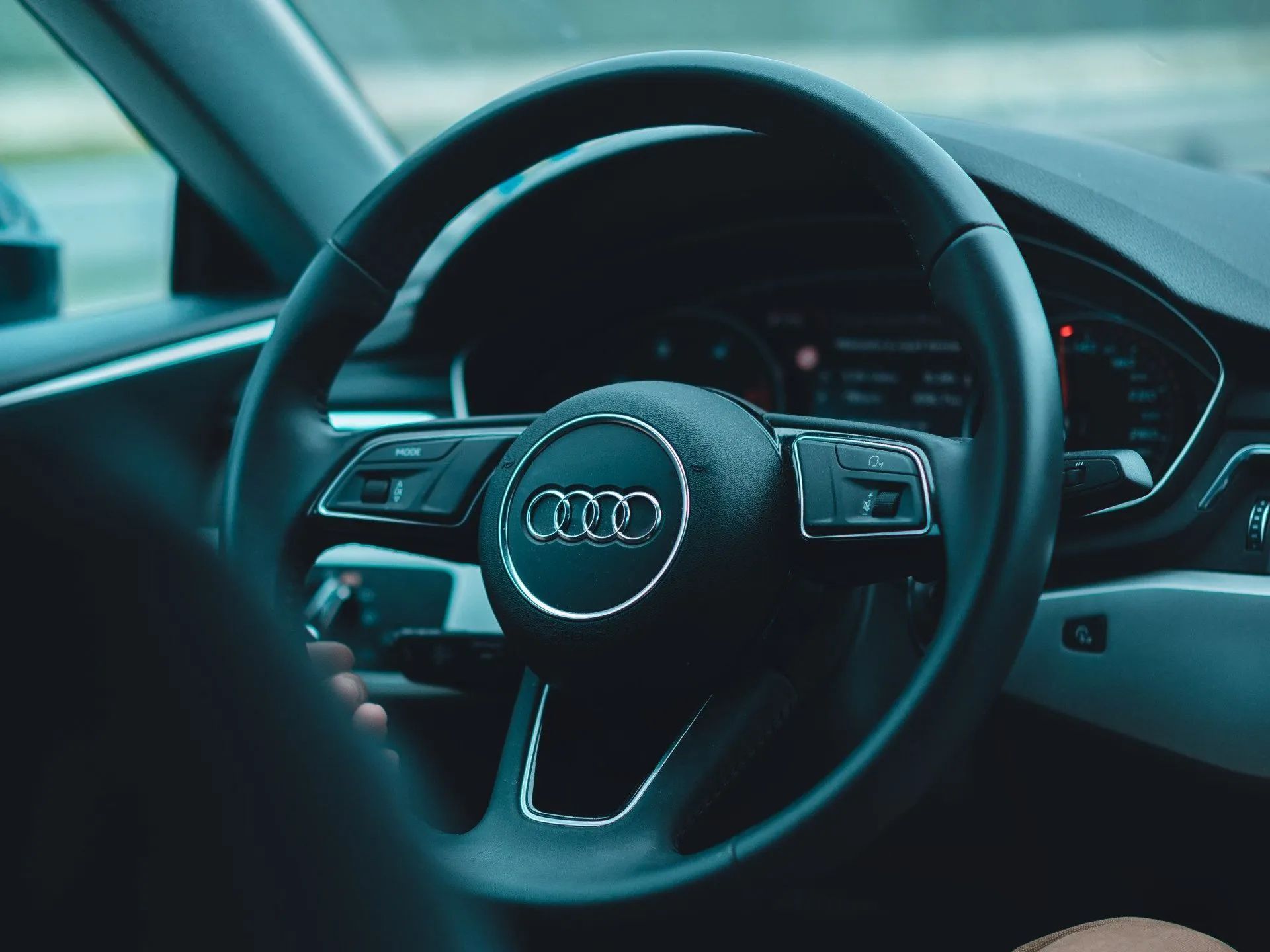 Audi steering wheel and dashboard inside a car, lit in blue tones