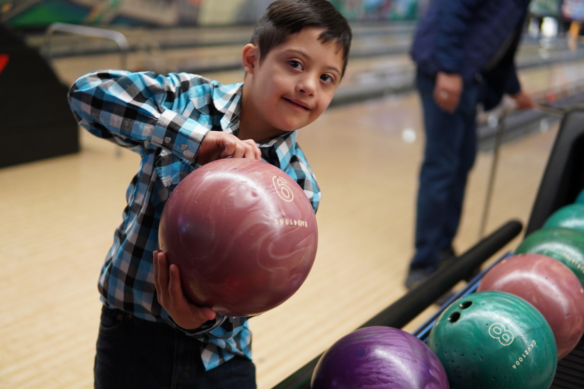Young athlete with down syndrome holds a bowling ball