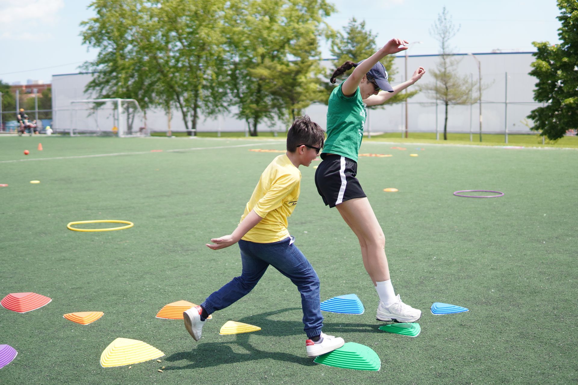 A volunteer and a KEEN Athlete jump across stepping stones together