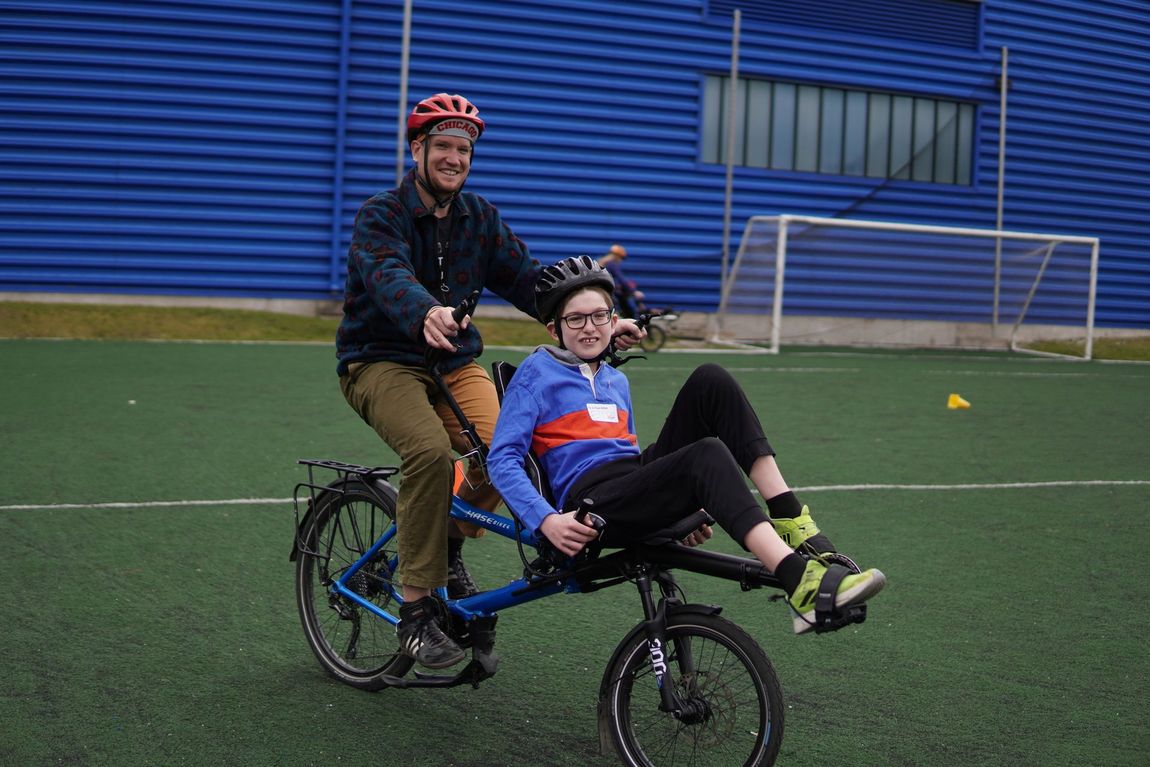 An athlete rides an adaptive bike with a volunteer