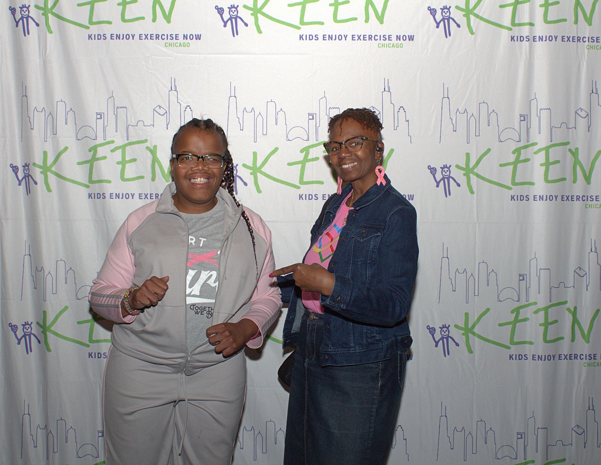 Two KEENFest guests pose in front of a logoed banner