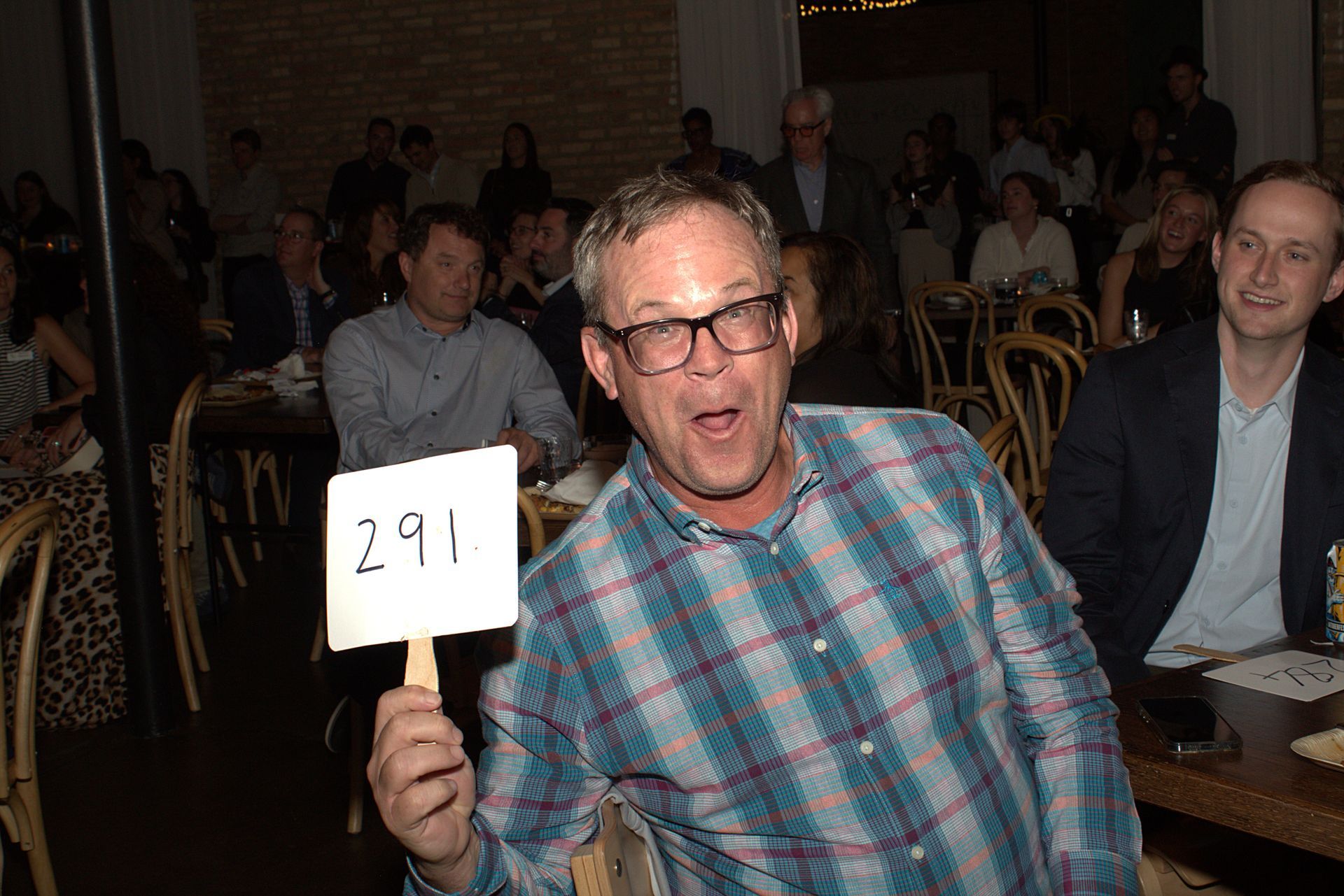 Attendee smiles and holds up his bid number