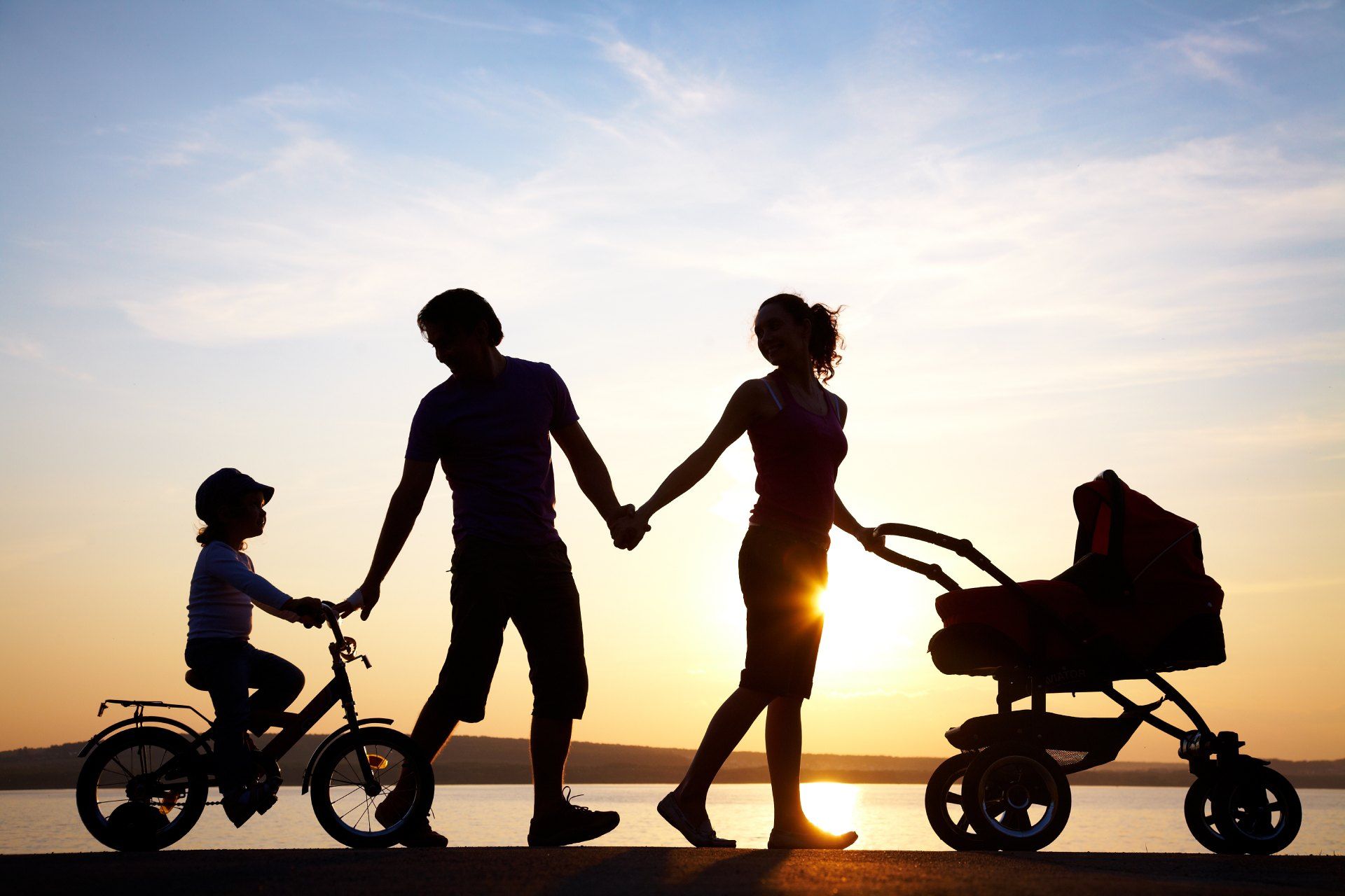 A family holding hands while a child rides a bike