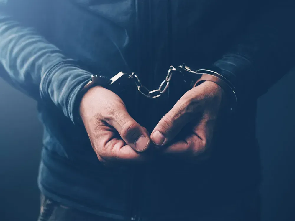 A man in handcuffs is sitting at a table talking to a man in a suit.