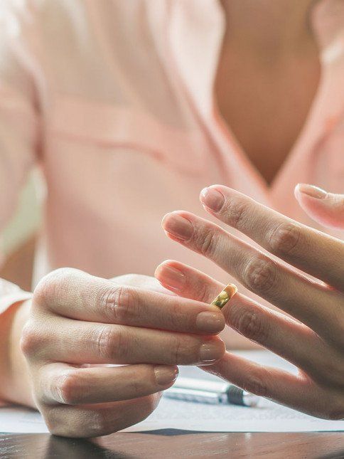 A woman is putting a wedding ring on her finger.