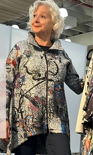 Woman with white hair smiles, wearing a patterned jacket with a black zip.