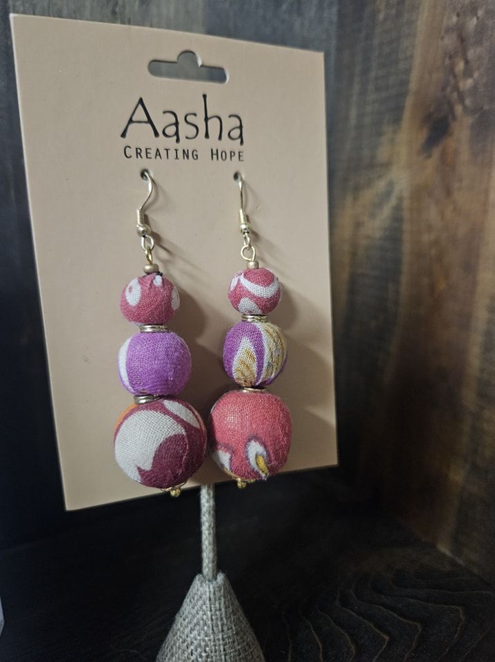 Earrings with three fabric-covered beads in shades of pink, purple, and white.