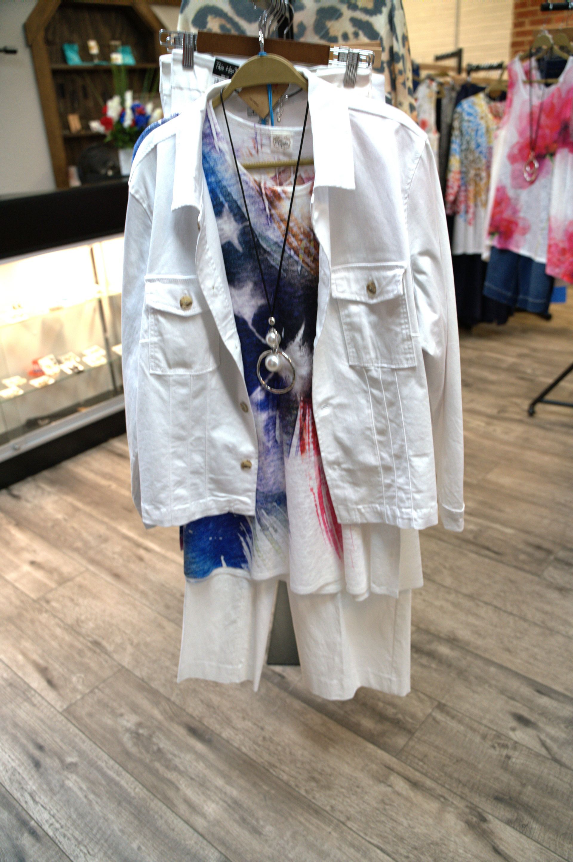 White denim jacket and layered white outfit on a hanger in a clothing store.