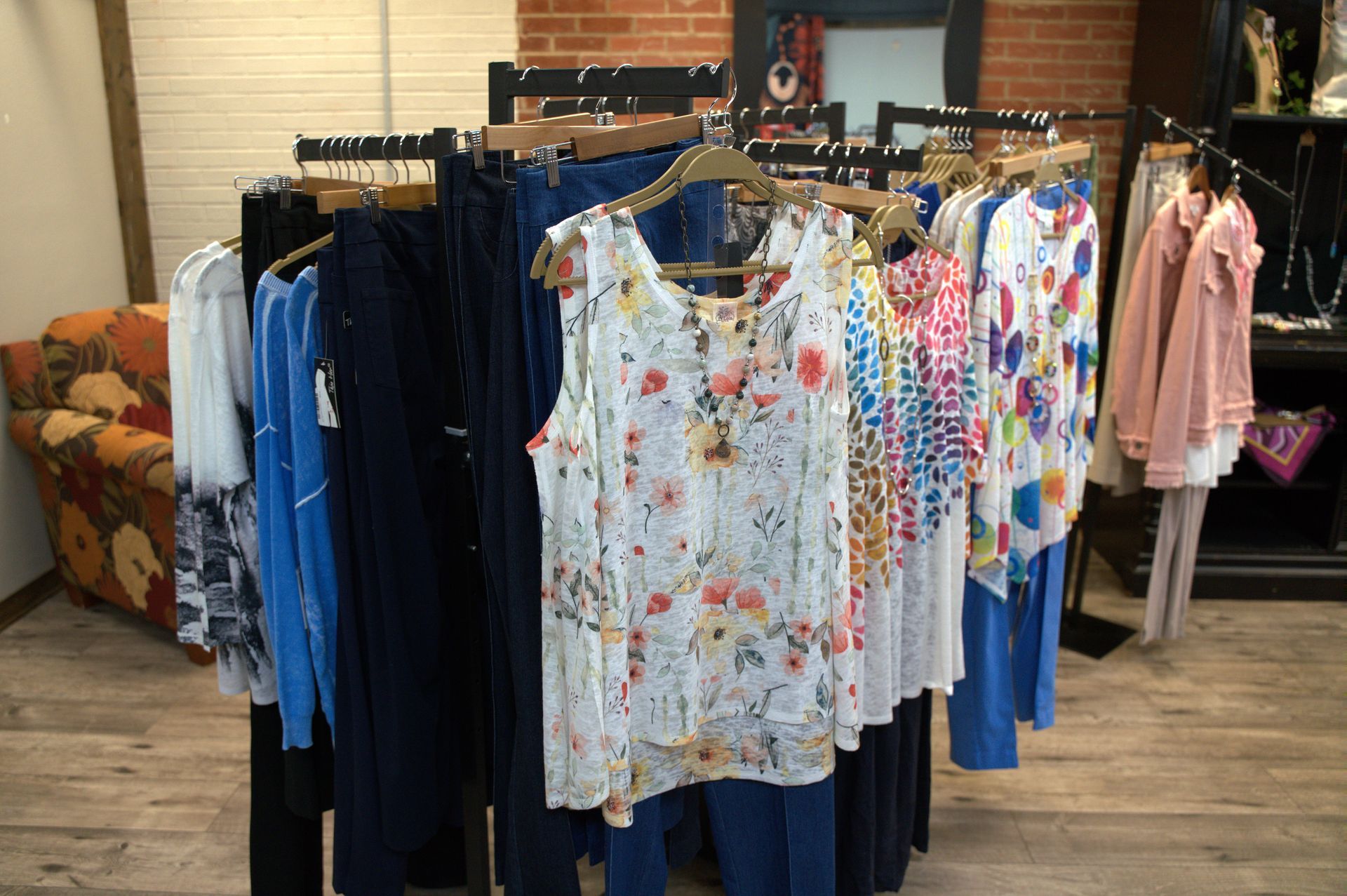 Clothing racks in a boutique, showcasing tops, pants, and jackets.