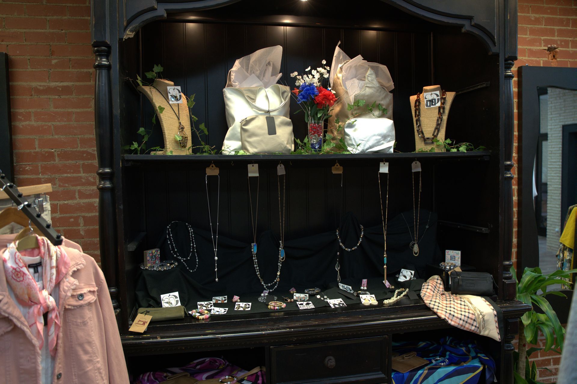 Jewelry display in a dark cabinet. Necklaces hang against black fabric, with some on display stands and other accessories.