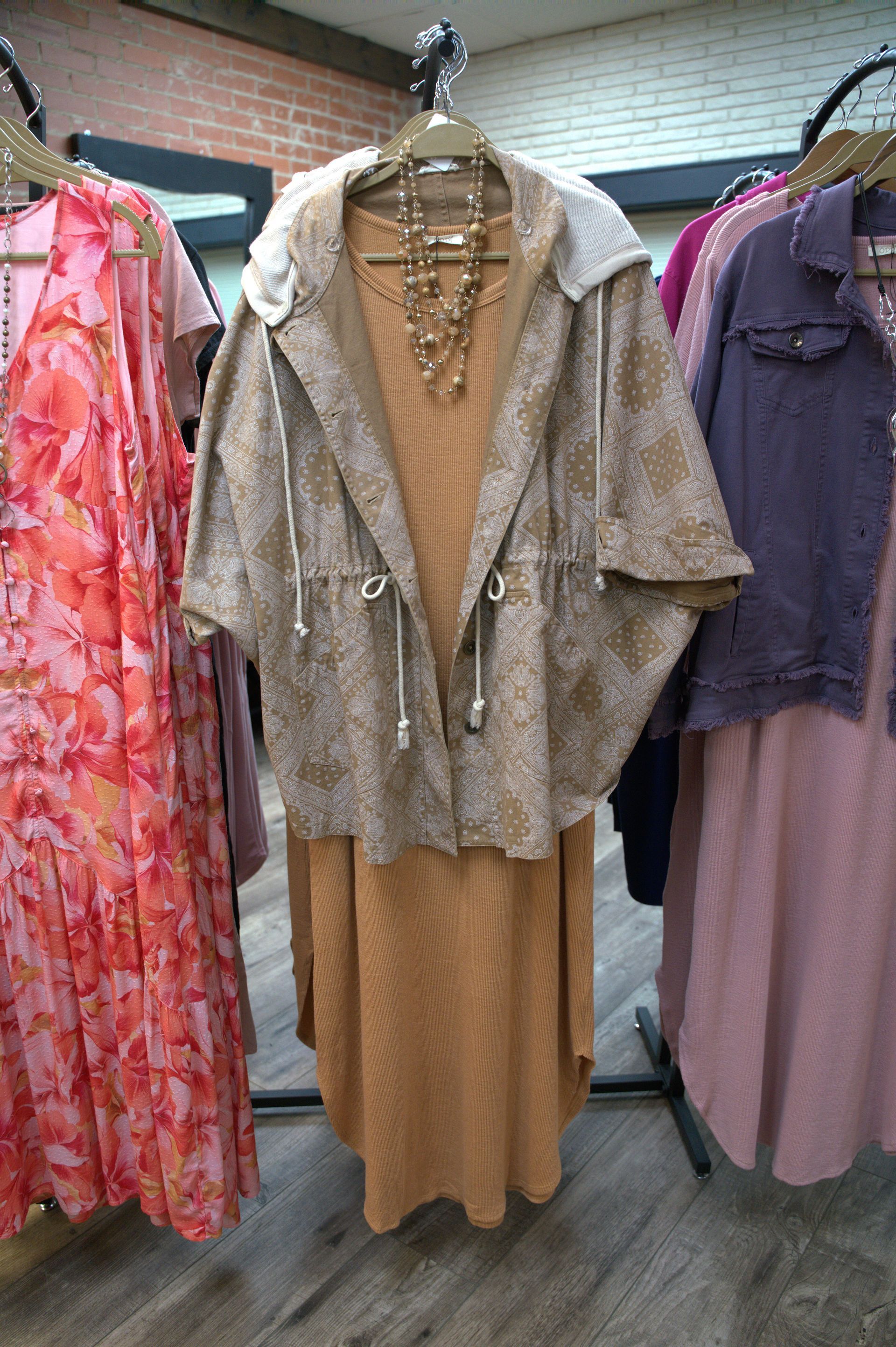 Clothing display: A tan hooded jacket with a drawstring, worn over an orange dress.