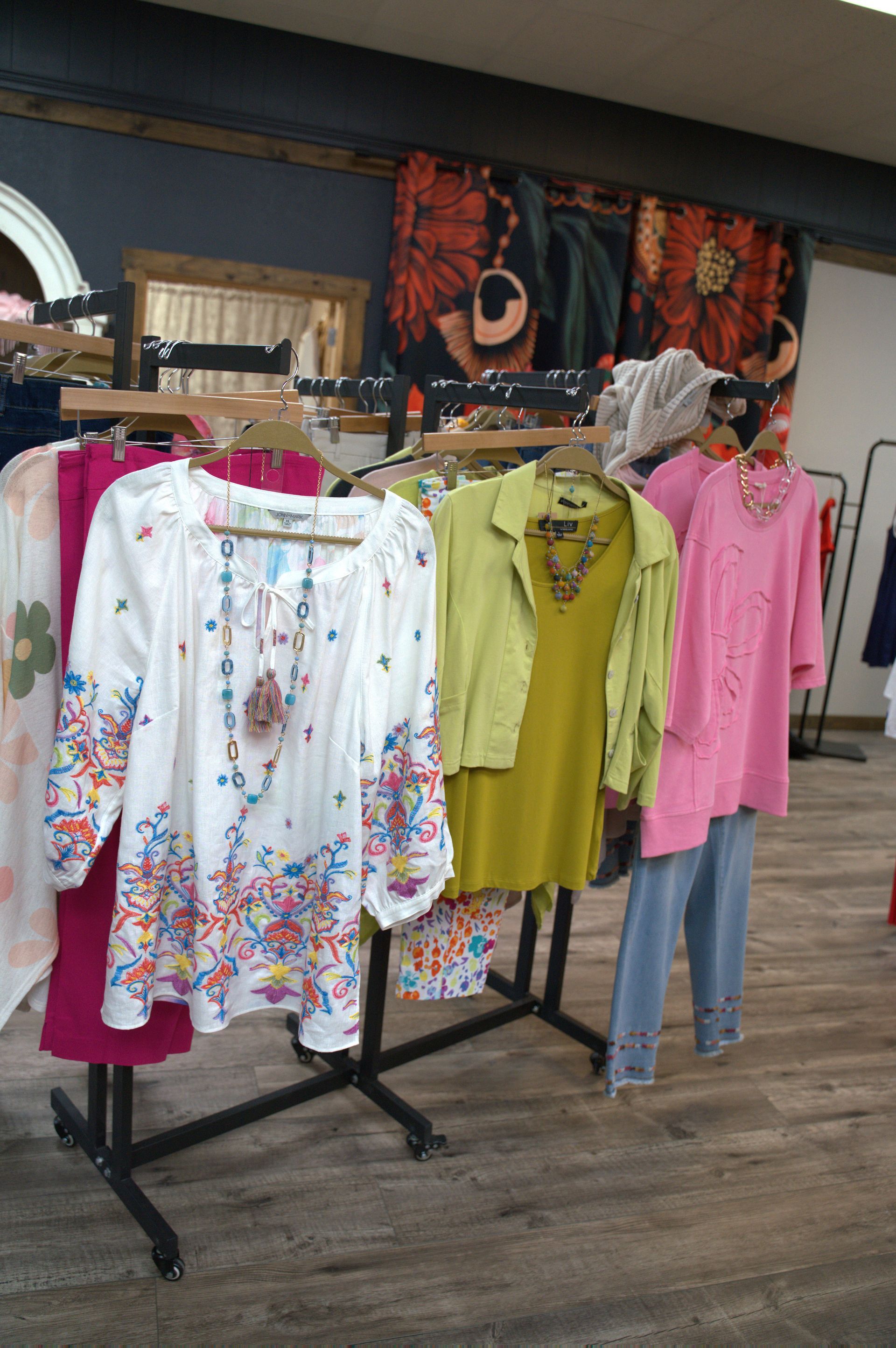 Clothes rack in a store displays colorful tops and jeans.