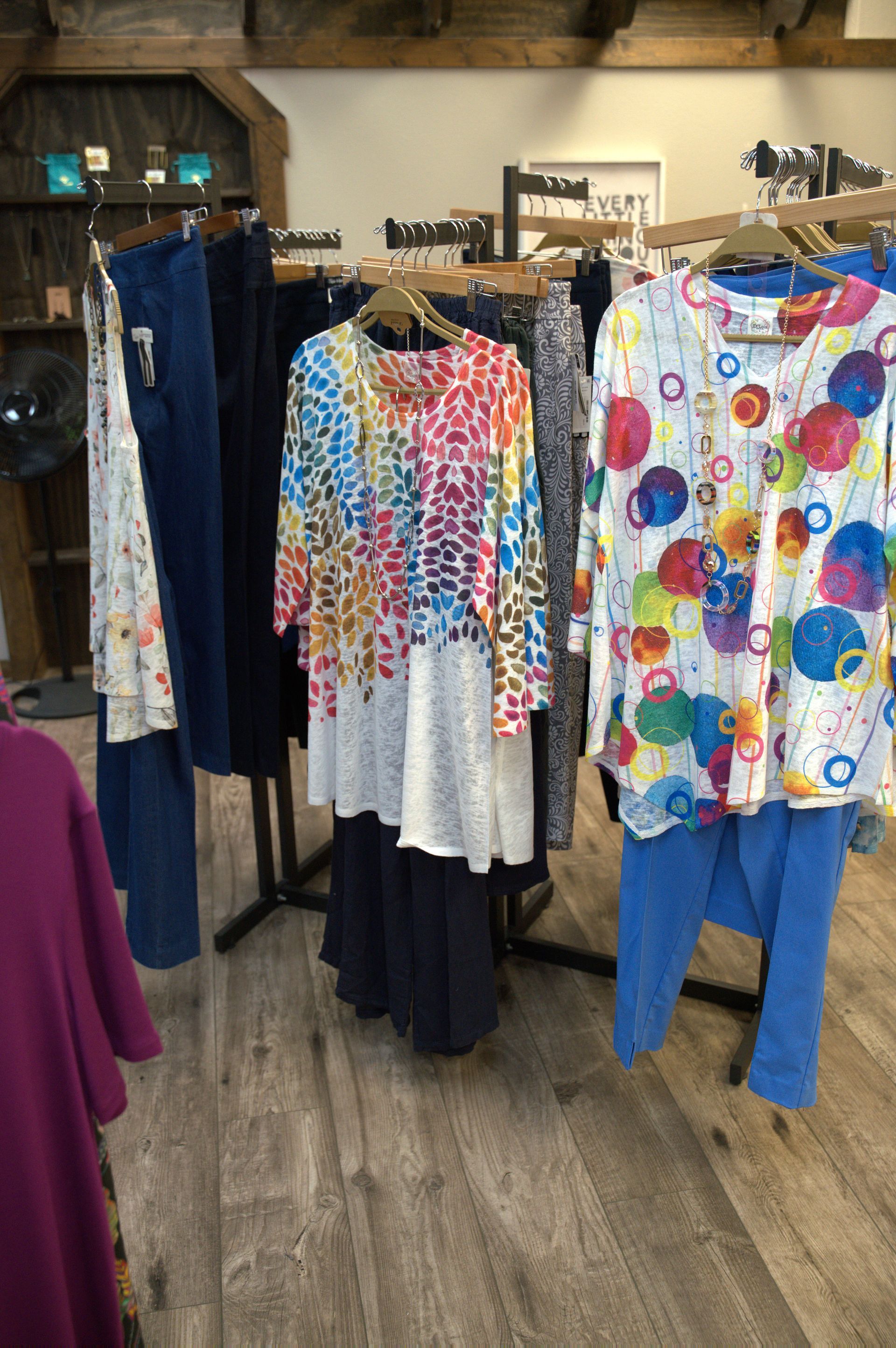Clothing store display featuring colorful tunics and pants on racks.