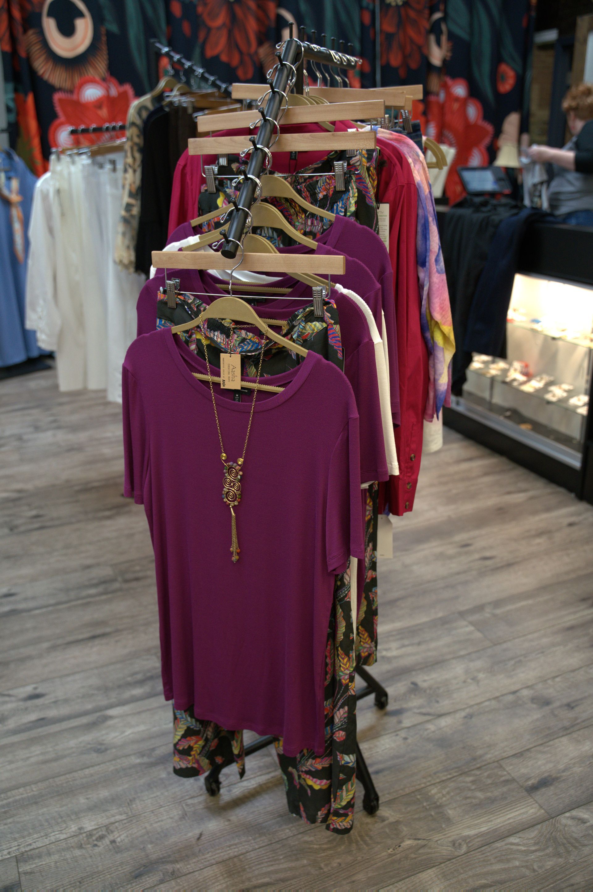 Clothing rack displaying shirts and pants in a clothing store. A purple shirt and patterned pants are in the foreground.