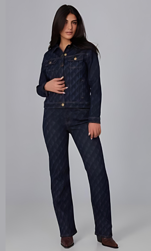 Woman wearing a dark denim jacket and matching pants, posing in a studio setting with a light gray background.