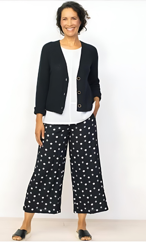 Woman wearing a black cardigan, white top, and black and white polka dot wide-leg pants.