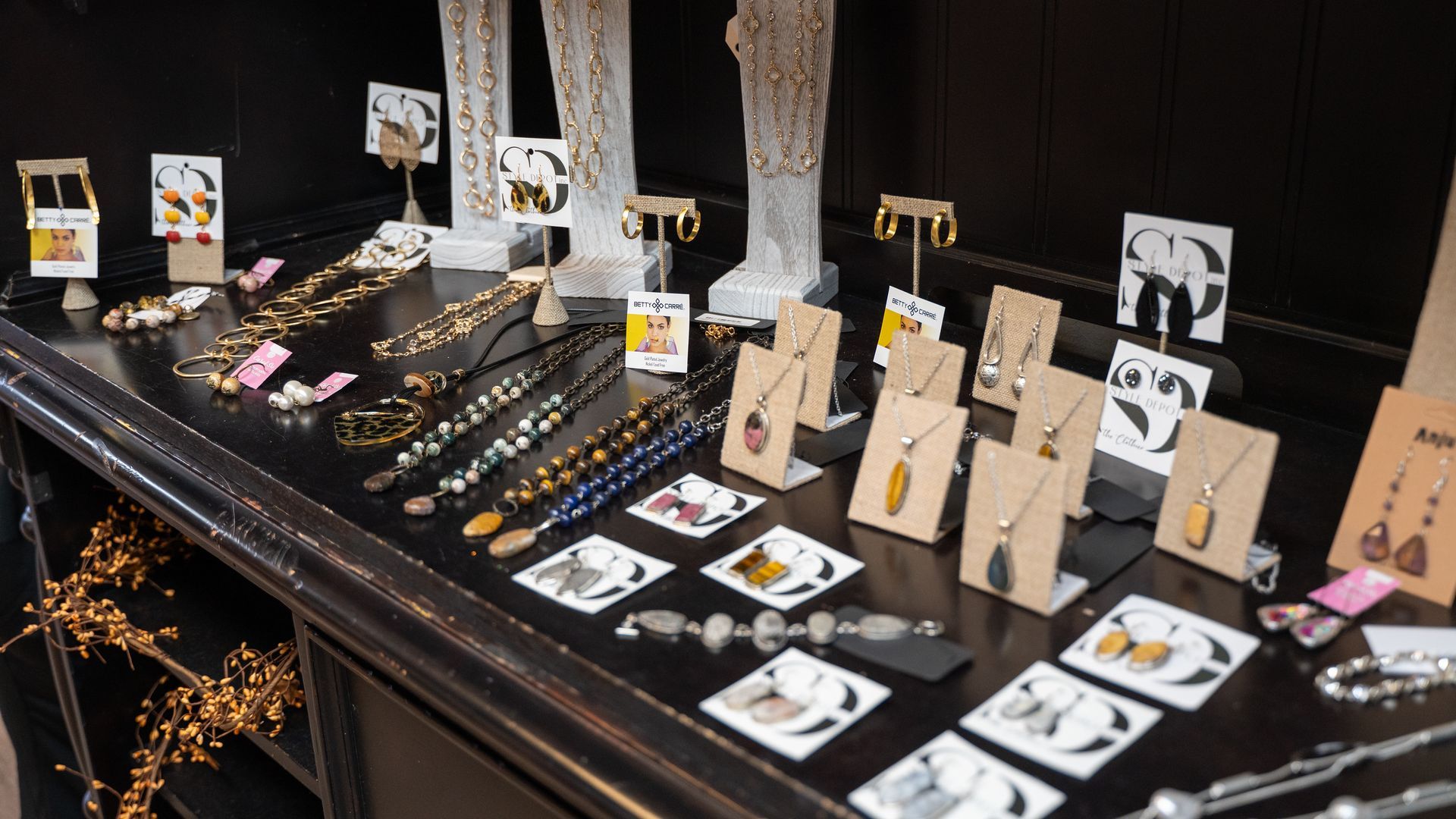Jewelry display with necklaces, earrings, and bracelets on a black surface.