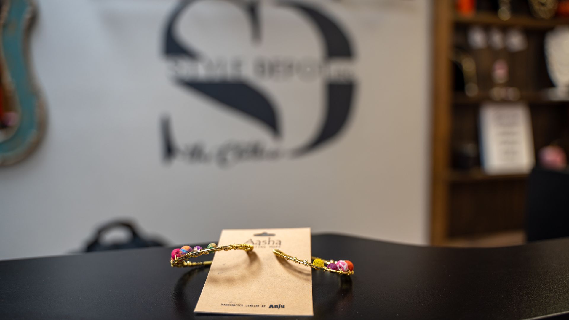 Bracelet on display in a shop, with a blurred logo in the background.