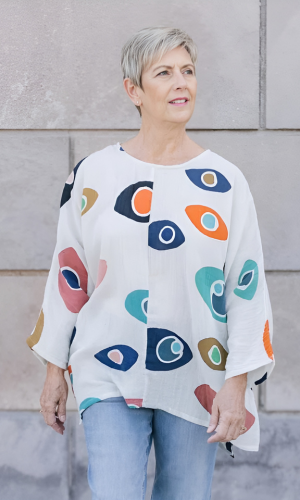 Woman with short blonde hair standing outside with a wall background.