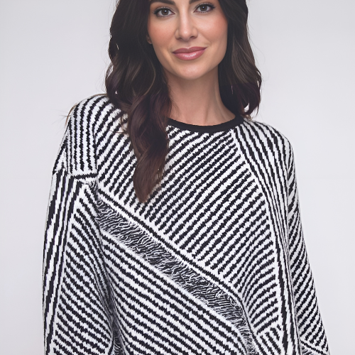 Woman wearing a black and white geometric patterned sweater, smiling, against a white backdrop.