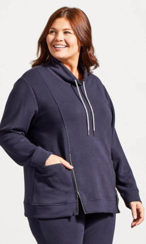 Woman in navy blue sweatshirt with a zipper and pockets, smiling and looking to the side.