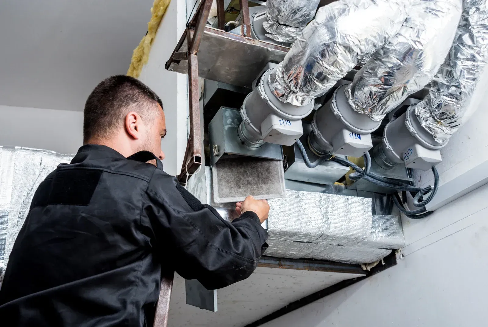 A person is cleaning an air conditioner with a spray bottle.