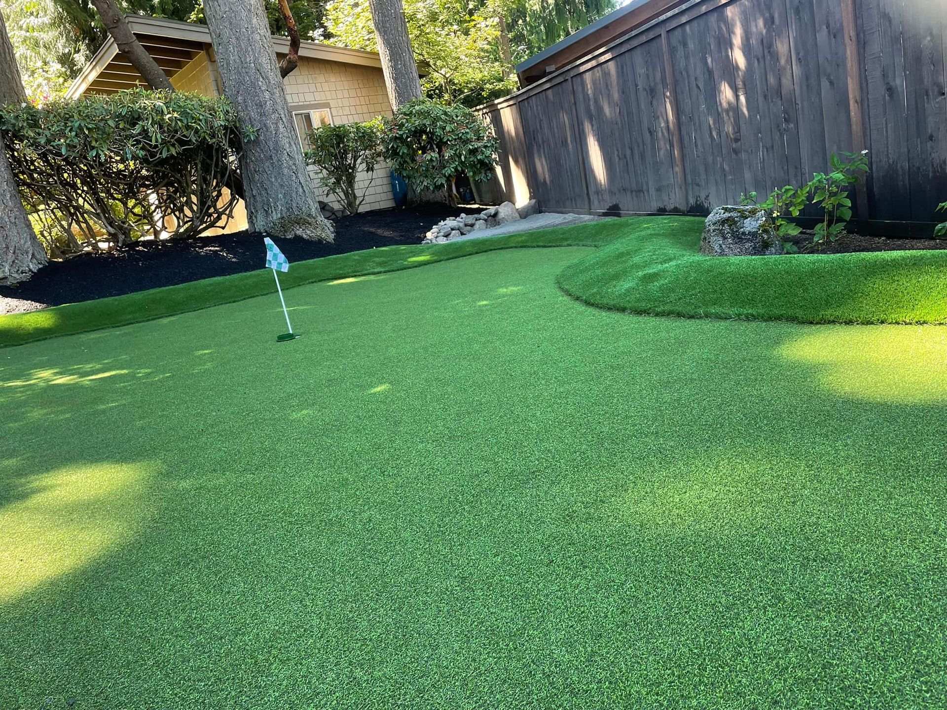 There is a putting green in the backyard of a house.